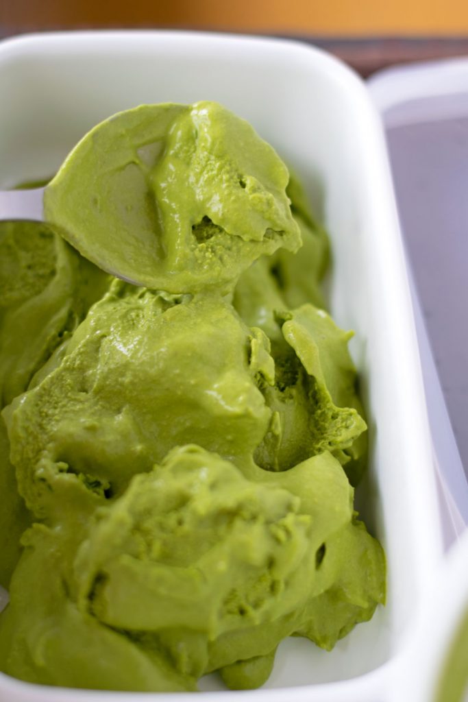 putting matcha ice cream in freezer container by spoon