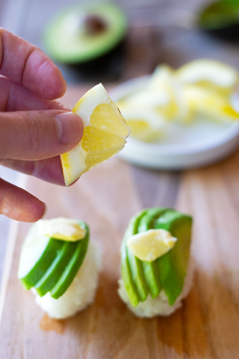 squeezing lemon slice on avocado sushi