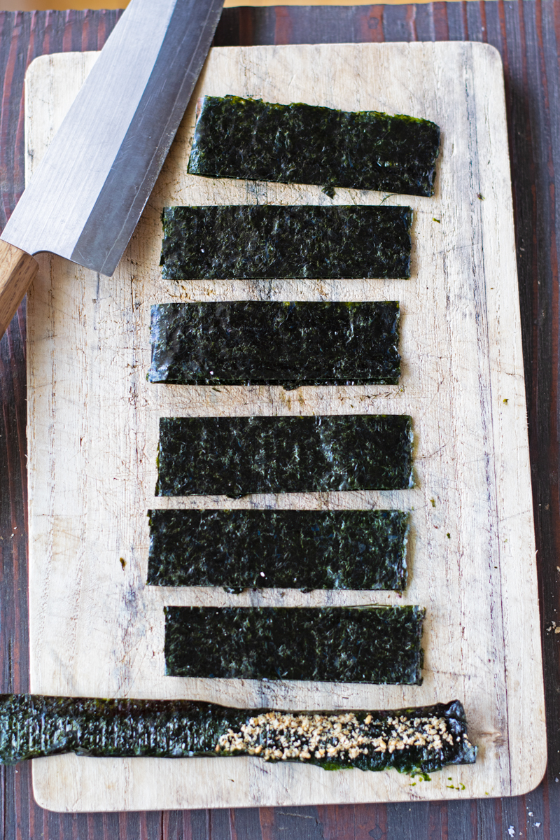 cut slices of nori seaweed sheet with ground sesame seeds on top