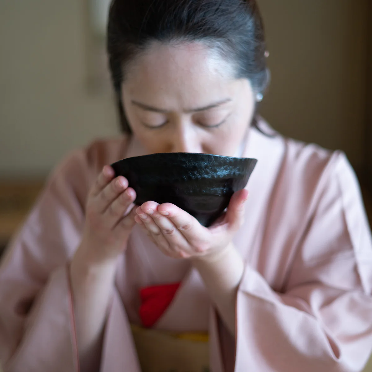 Japanese woman in kimono drinking matcha from chawan tea bowl