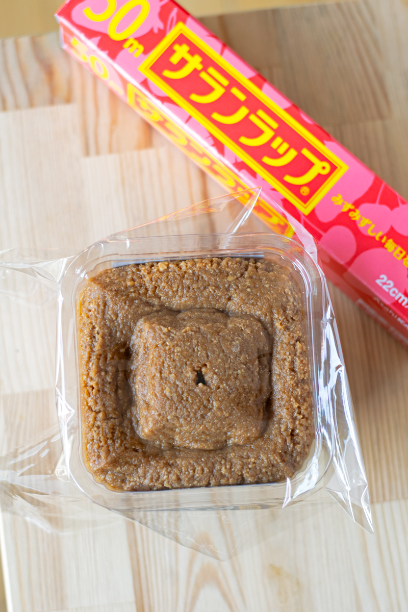 container of miso paste covered with plastic wrap
