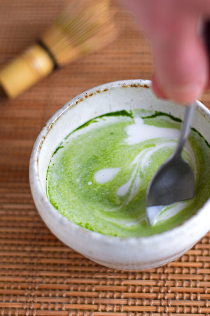 coconut matcha latte being stirred with a spoon