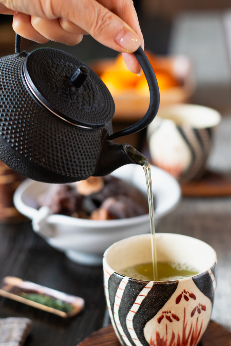 Japanese tetsu iron teapot pouring green tea into tea cup