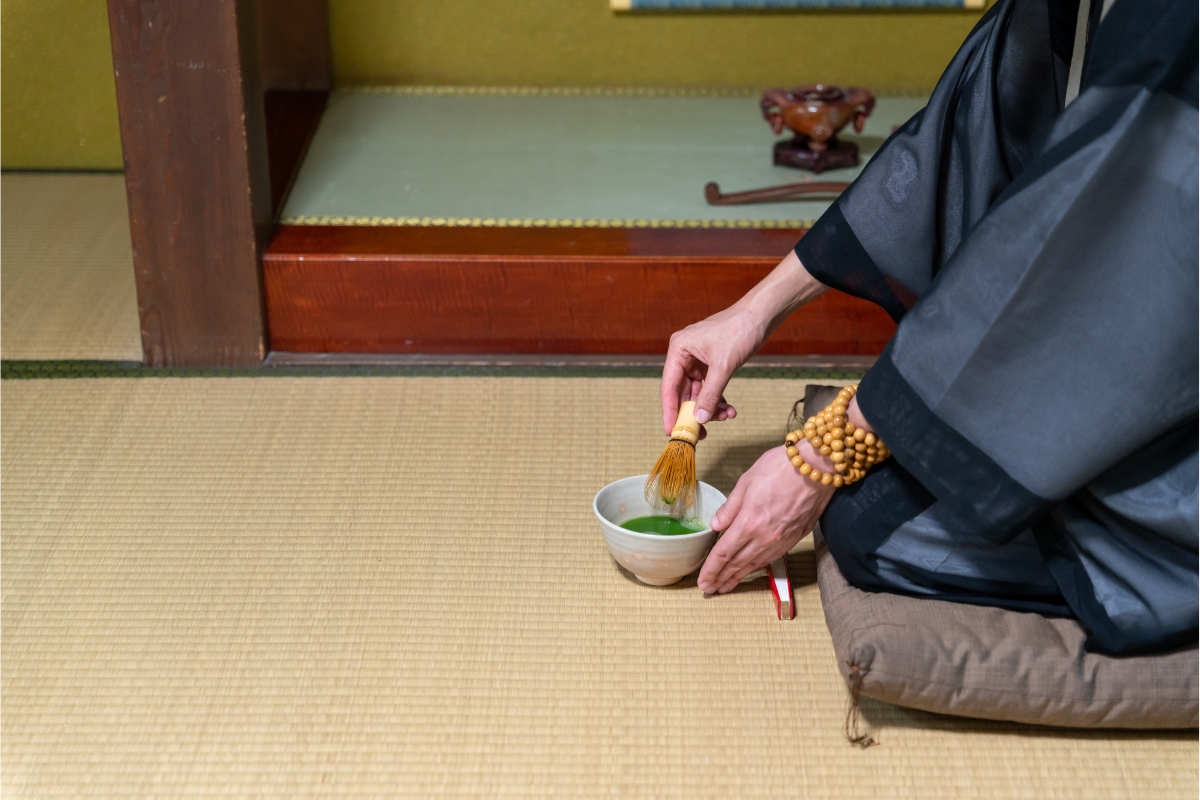 Japanese Zen monk sitting on a cushion in a tamami room making matcha