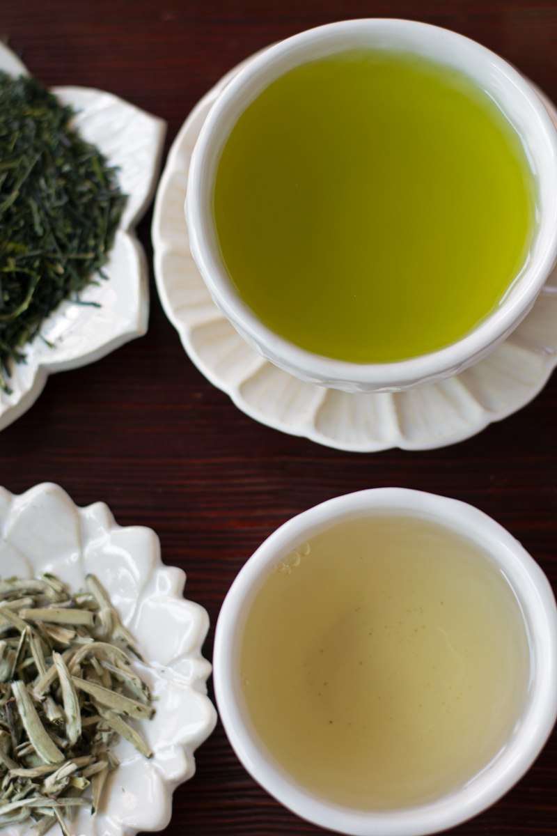 green tea and white tea next to tea leaves 