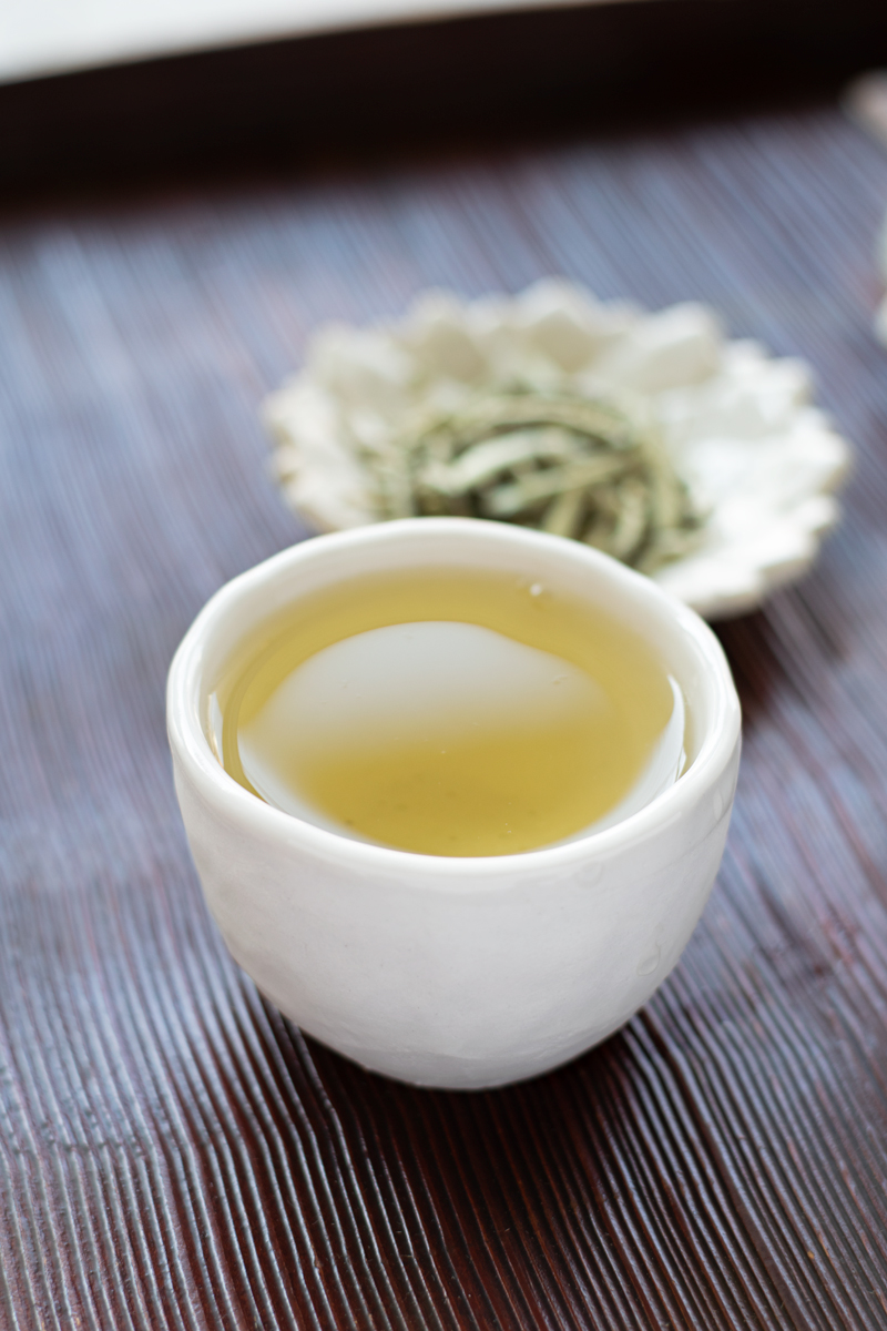 cup of white tea with white tea leaves in the background