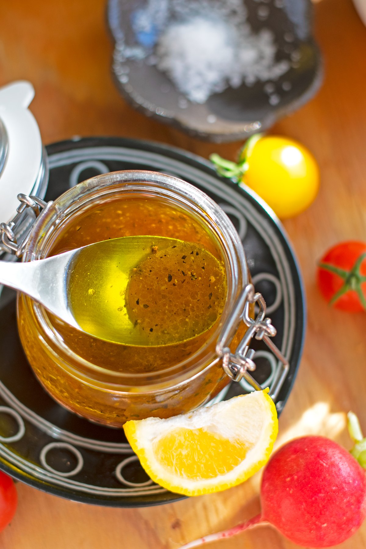 Spoonful of yuzu dressing showing the separation of oil and vinegar directly above a jar filled with dressing.