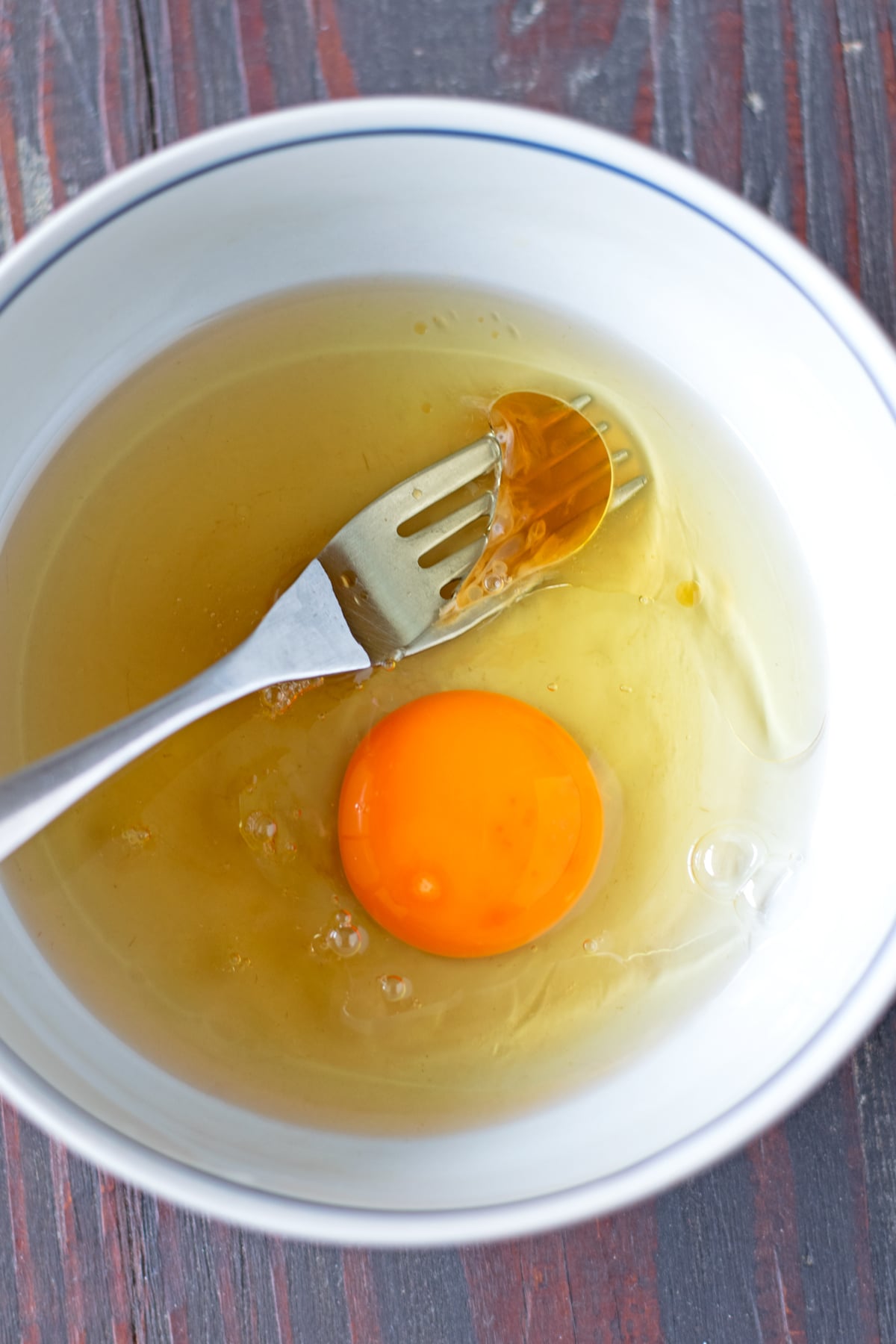 Mixing wet ingredients for cookies in bowl with spoon.