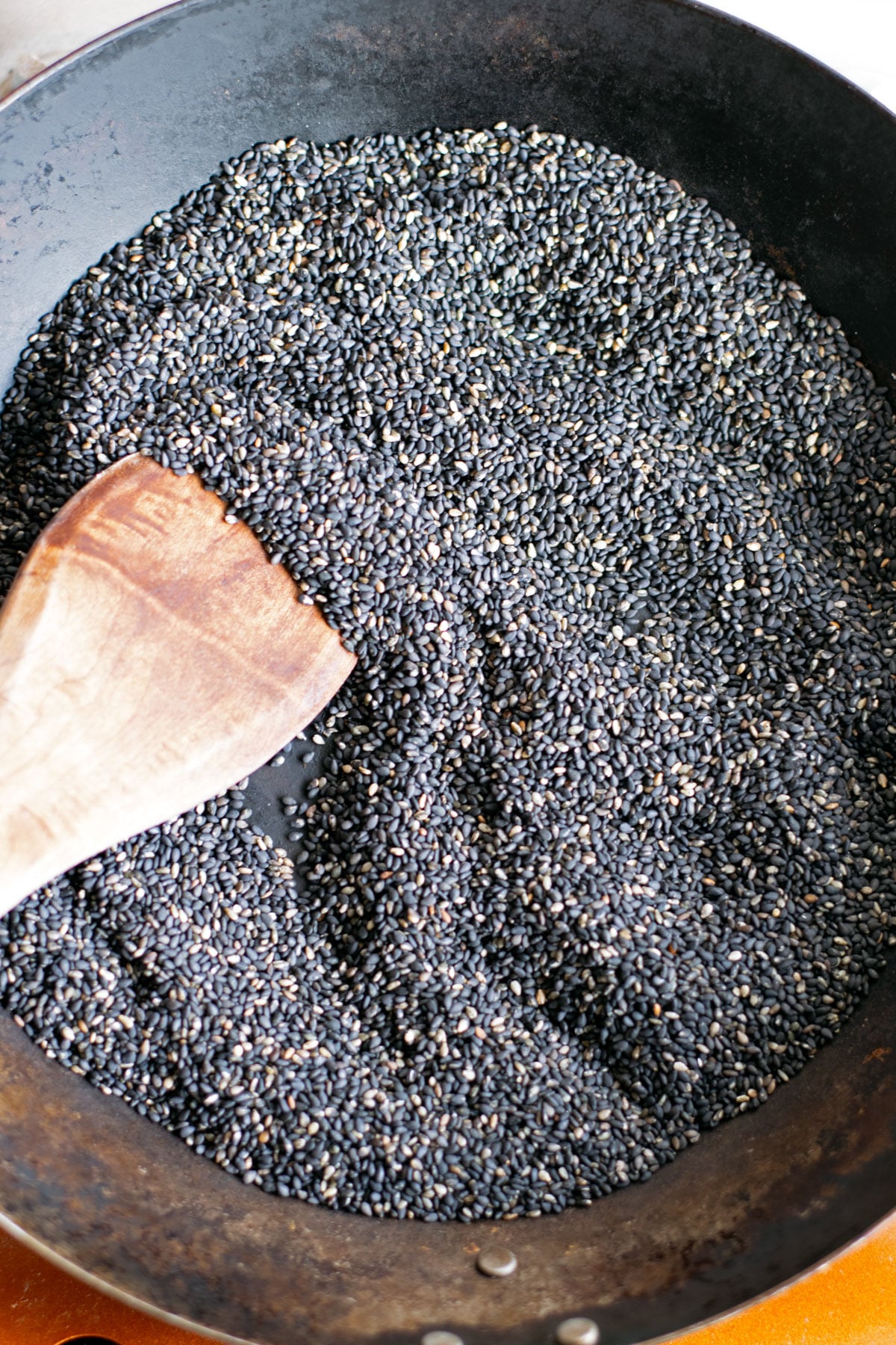 Black sesame seeds toasting in a pan before making sesame paste.