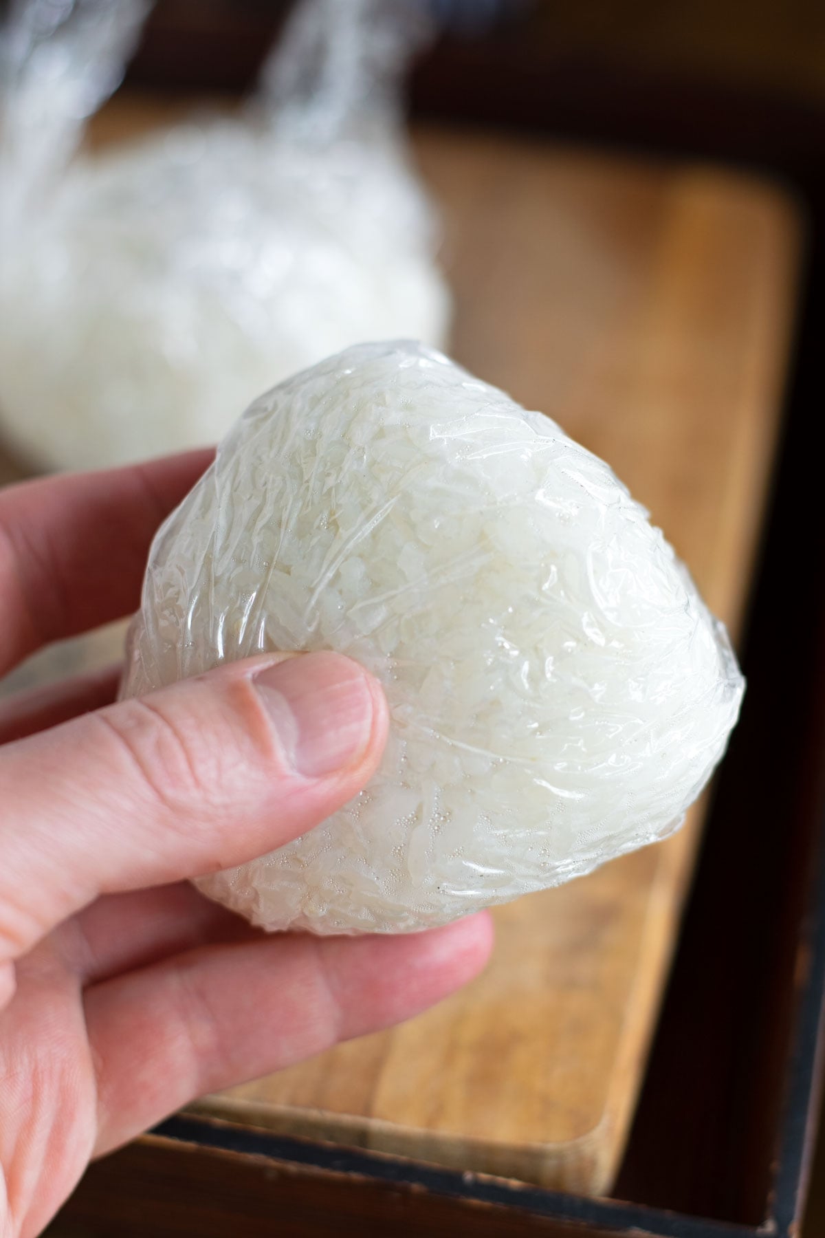 Onigiri wrapped tightly in plastic wrap for storage.