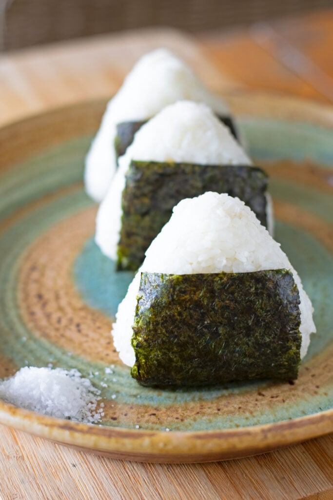 3 shio onigiri wrapped with nori seaweed around the bottom covering about half of the onigiri.