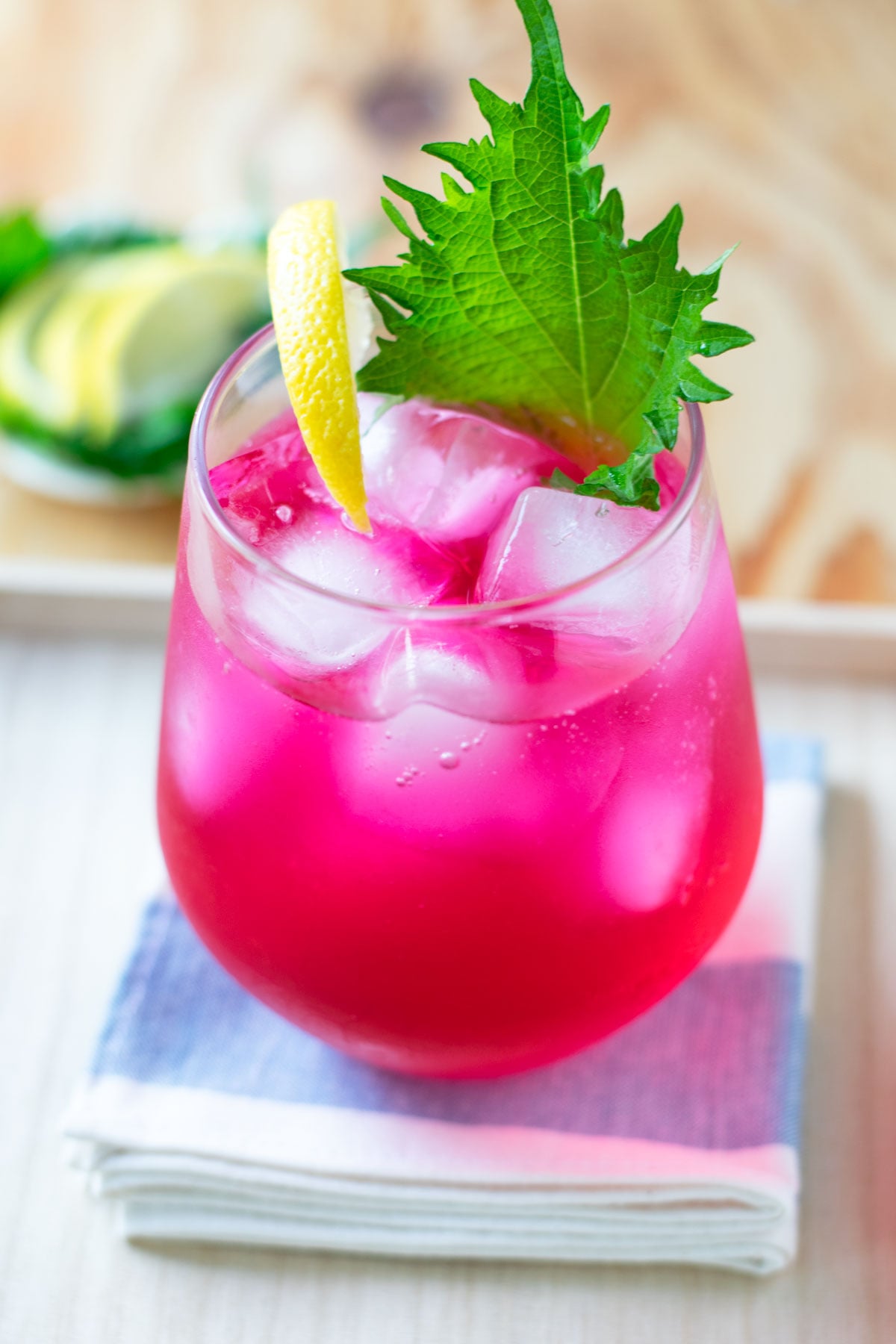 Refreshing red shiso juice garnished with lemon and a fresh green shiso leaf.