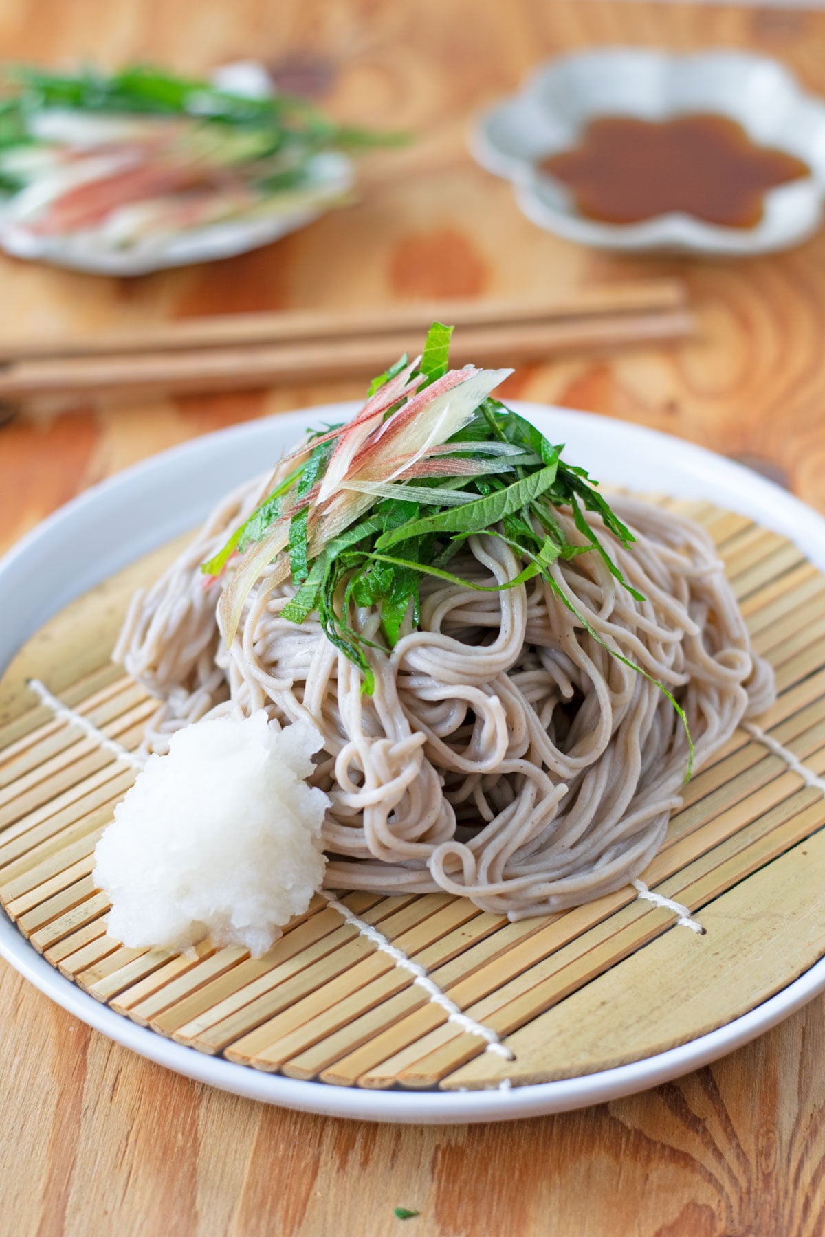 Cold soba noodles topped with shredded green shiso, sliced myoga ginger, and grated daikon oroshi.
