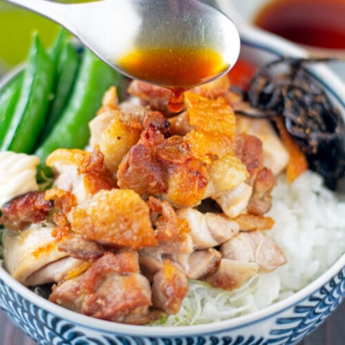 Spoon pouring yuzu sauce over bowl of grilled chicken and vegetables.