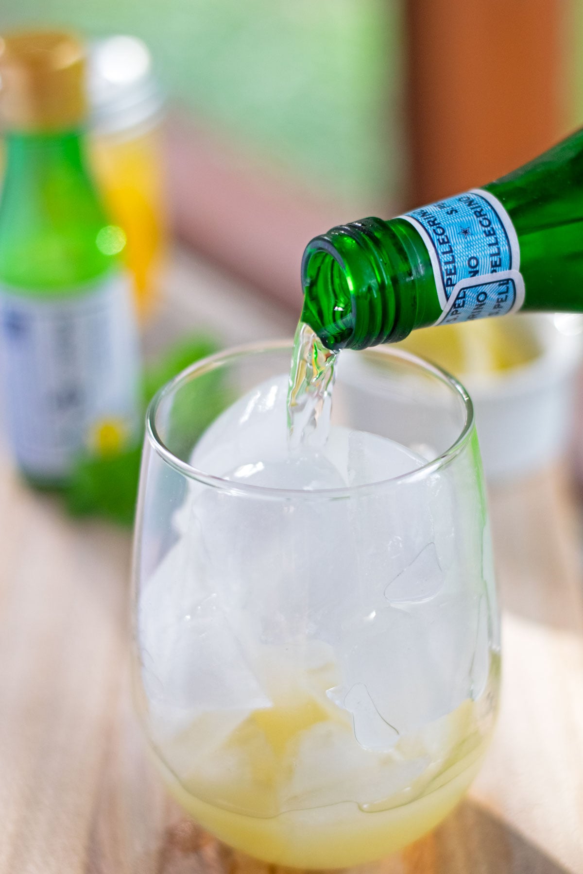 Sparkling water being poured into a glass of yuzu juice over ice to make a yuzu mocktail.