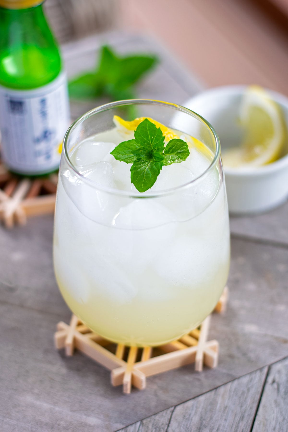 A glass of yuzu mocktail garnished with lemon and mint.