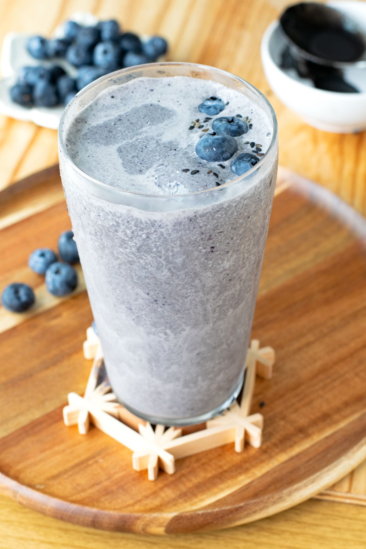 Black sesame smoothie with fresh blueberries and black sesame seeds sprinkled on top.