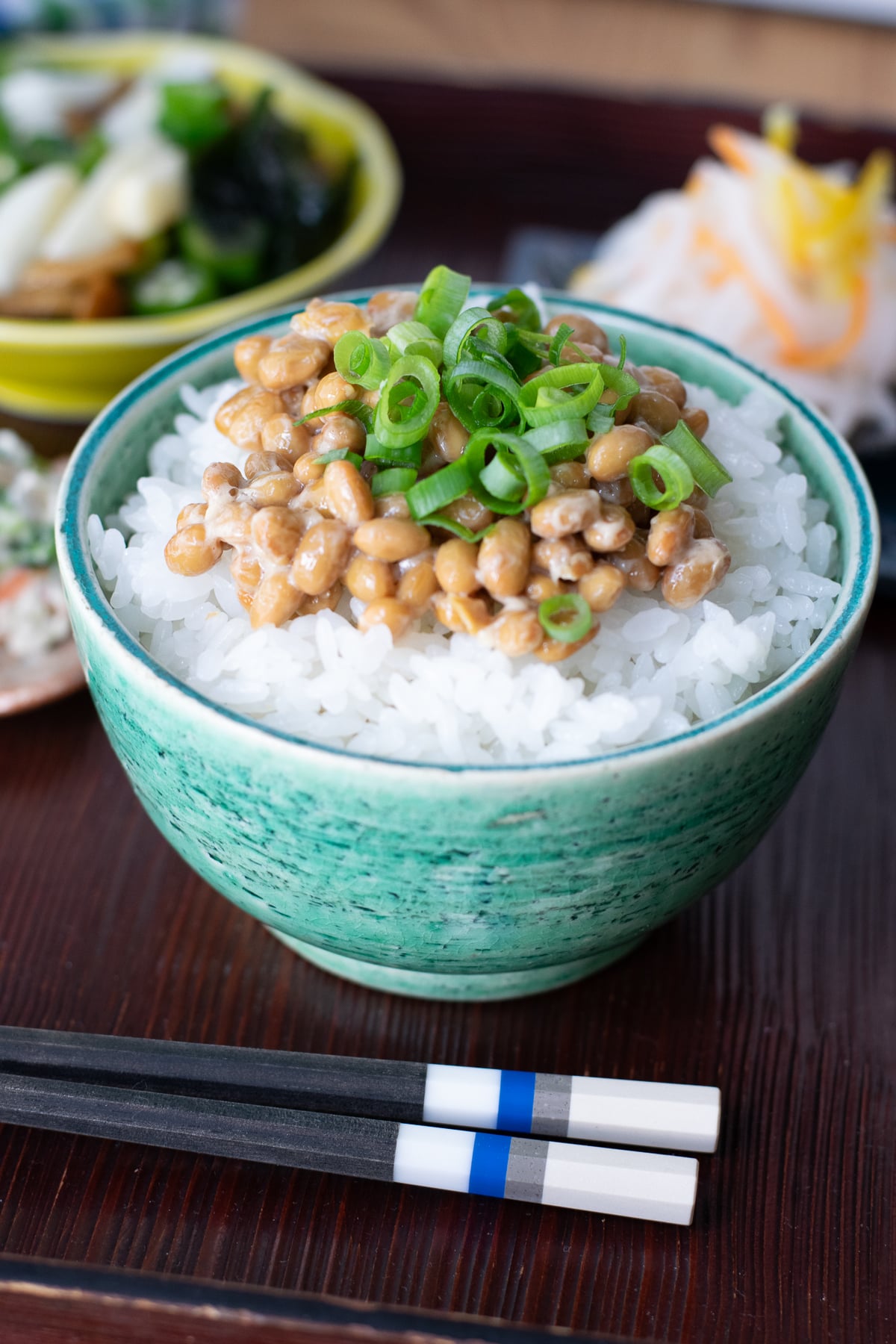 Bowl of white rice topped with natto and finely sliced green onion.