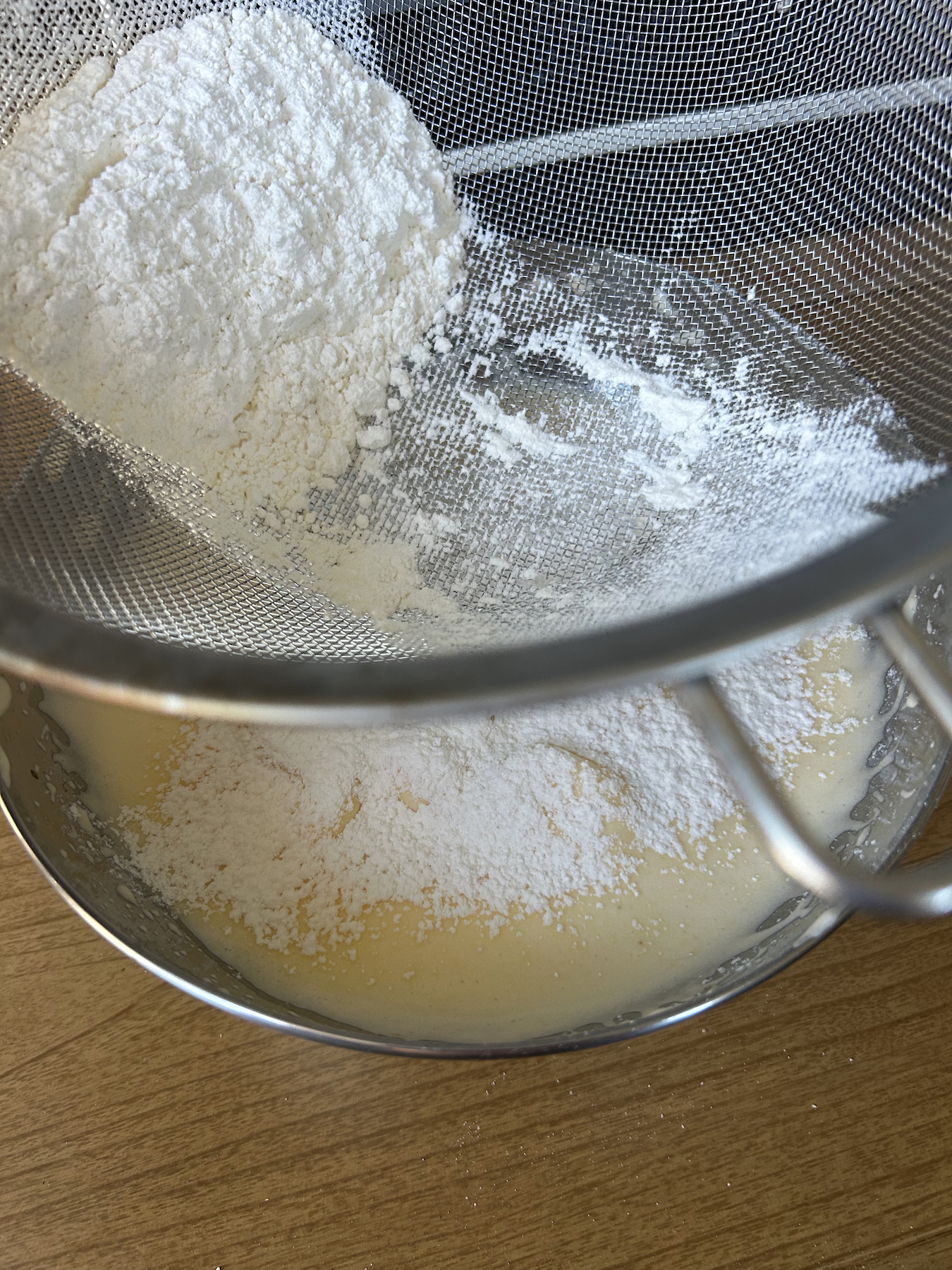Sifting flour into a mixture of egg and sugar.