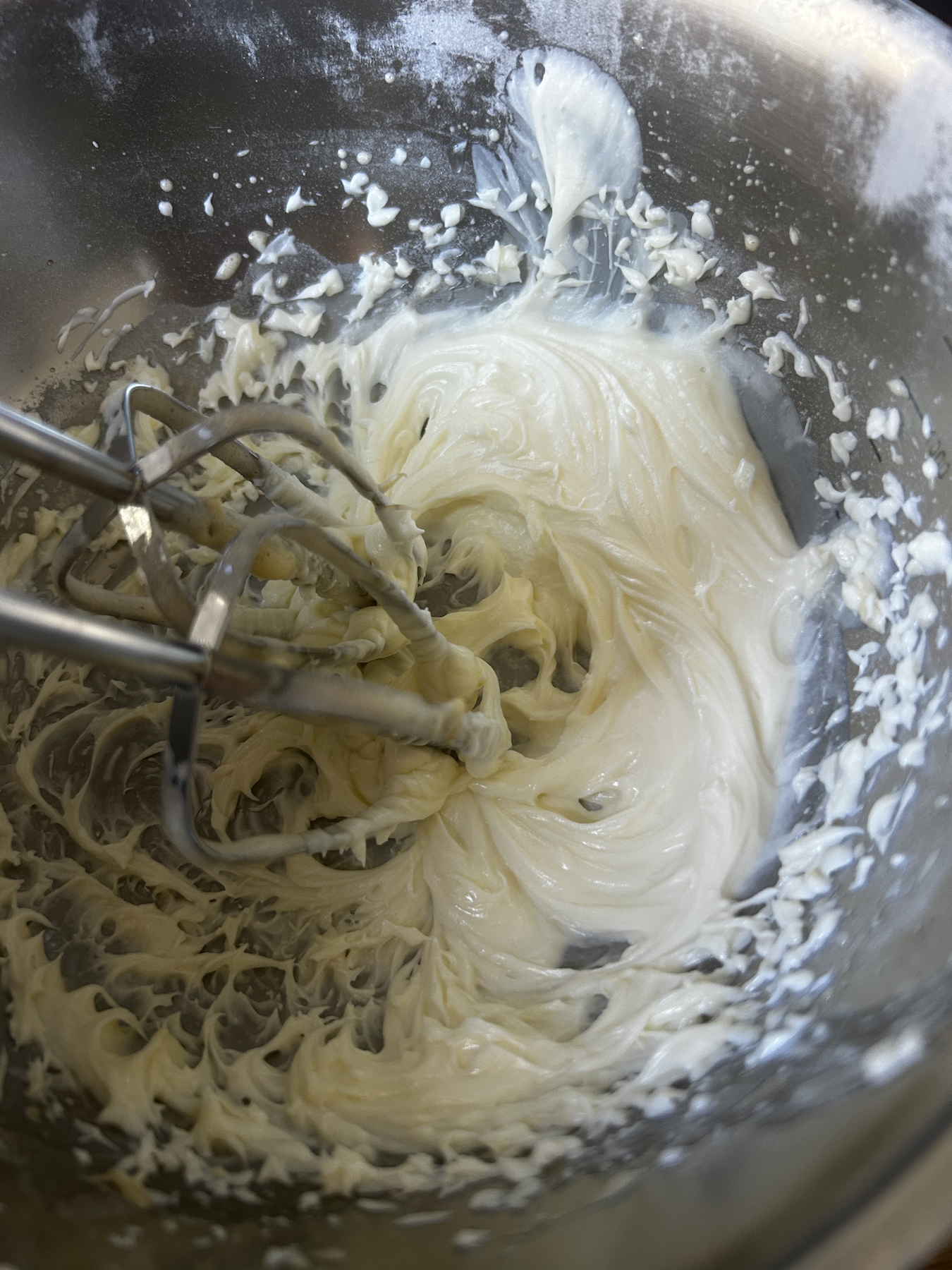 Beaters resting inside a bowl of batter made with sour cream, melted butter, and flour.