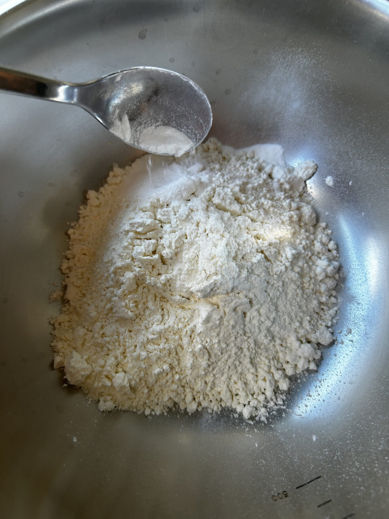 Adding baking powder to cake flour in bowl.