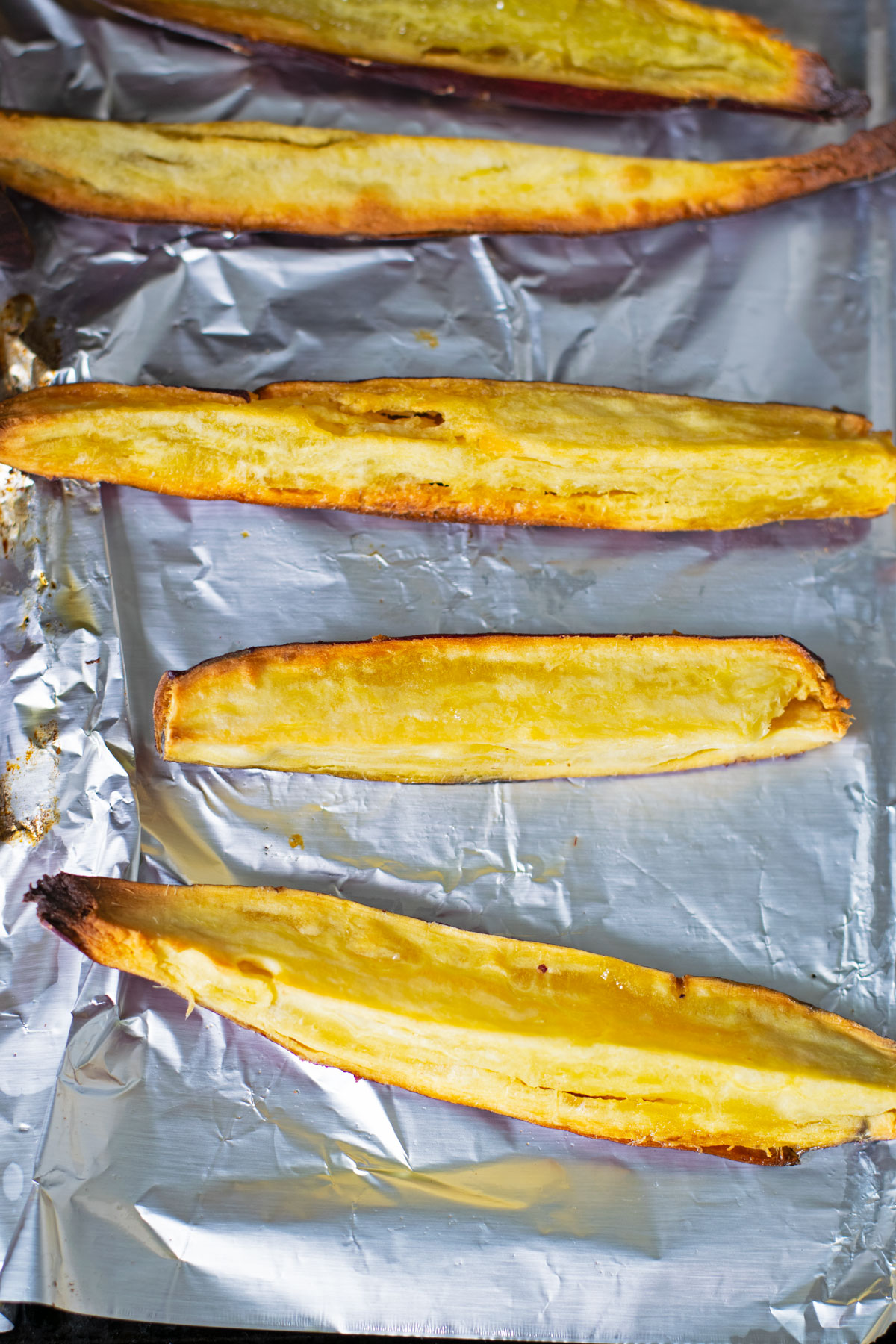 Roasted Japanese sweet potato wedges on top of foil.