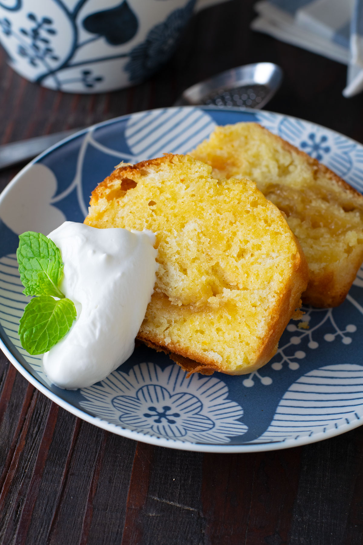 Two slices of yuzu cake with a dollop of whipped cream garnished with a spring of mint.