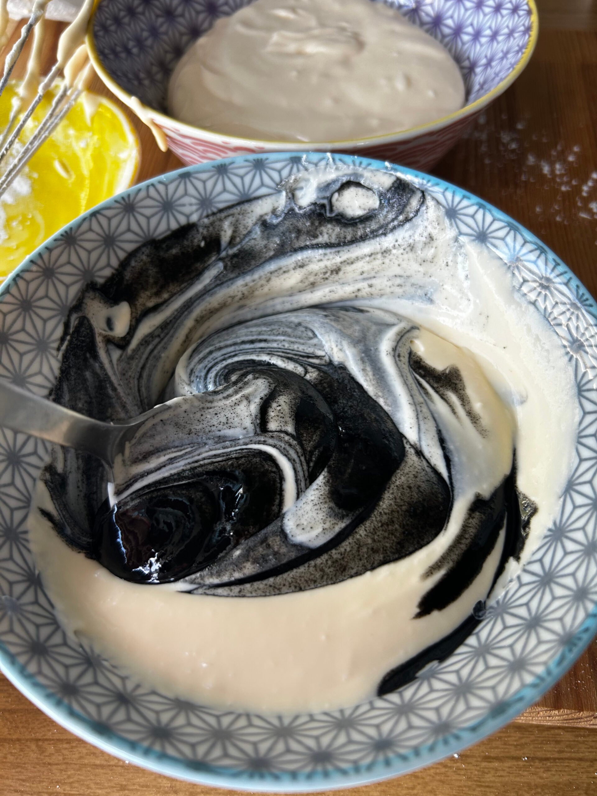 Mixing black sesame paste into a bowl of cheesecake batter.