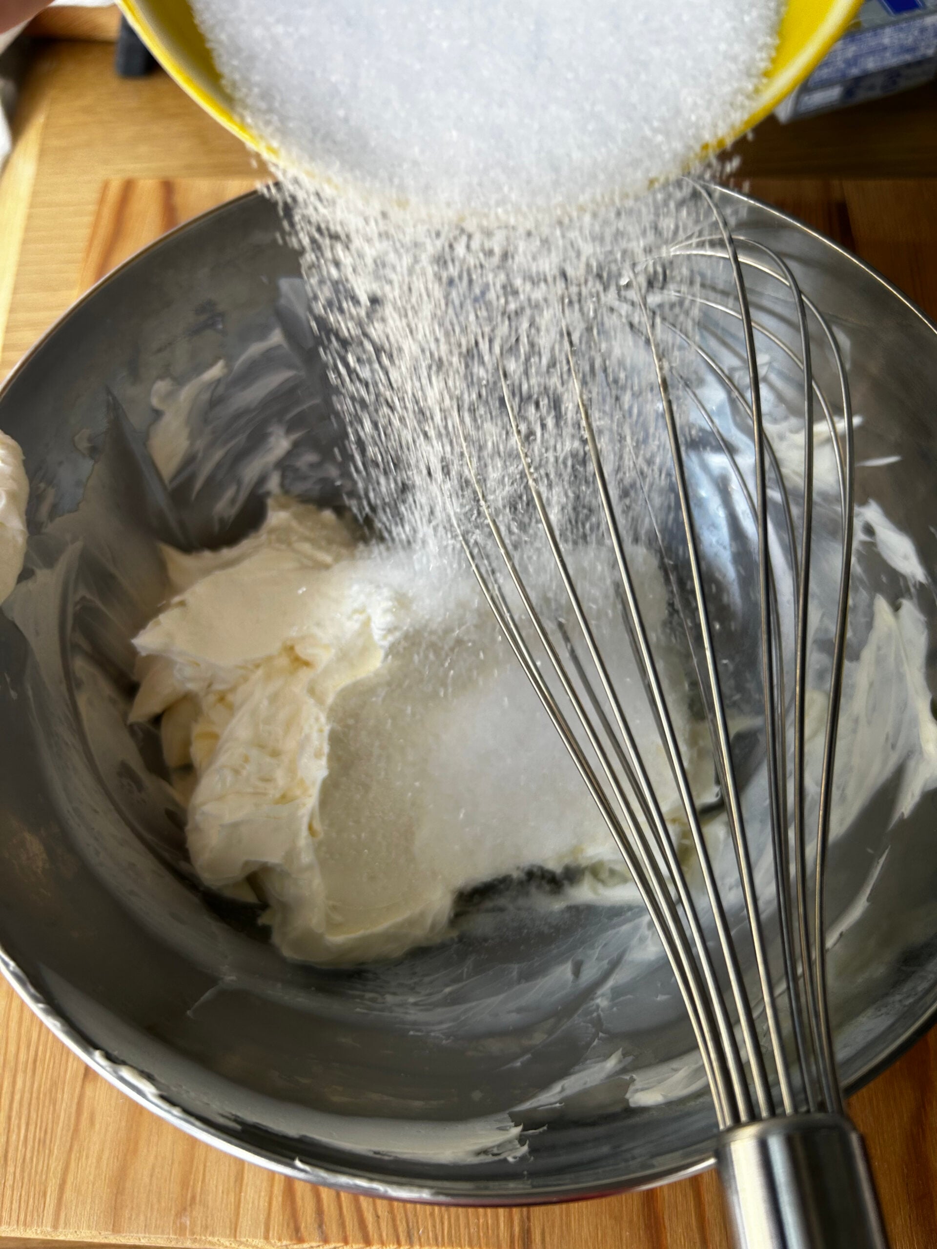 Adding sugar to a mixure of cream cheese and sour cream.