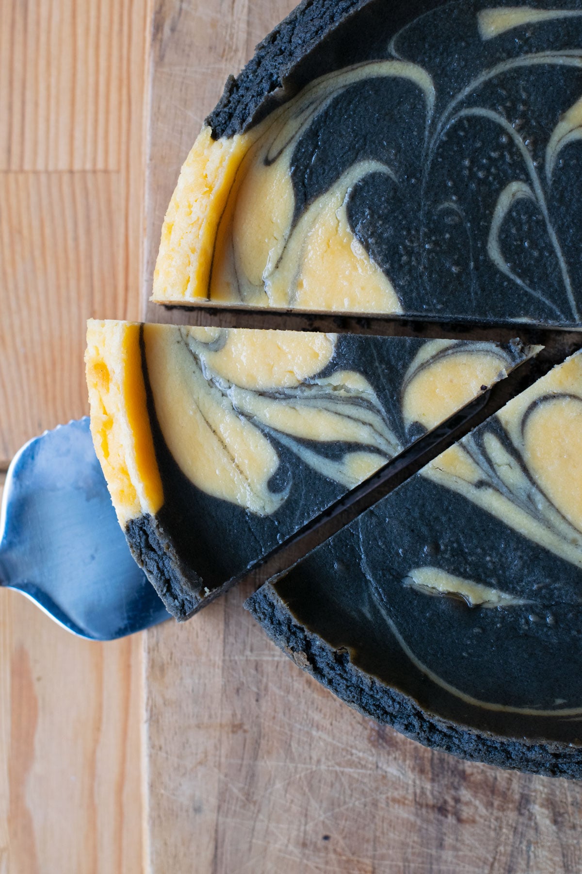 A slice of marbled black sesame cheesecake being lifted from the rest of the cheesecake.