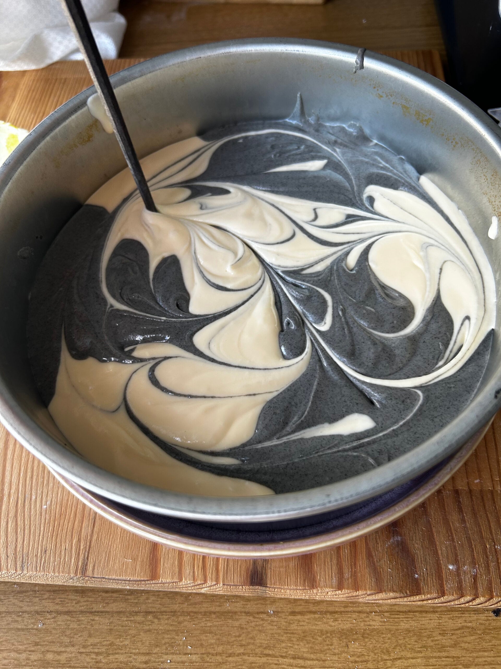Swirling the black sesame and plain cheesecake batter with a chopstick.