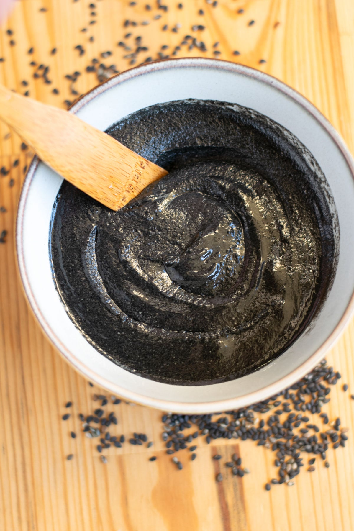 Bowl of homemade black sesame paste with wooden stir stick.